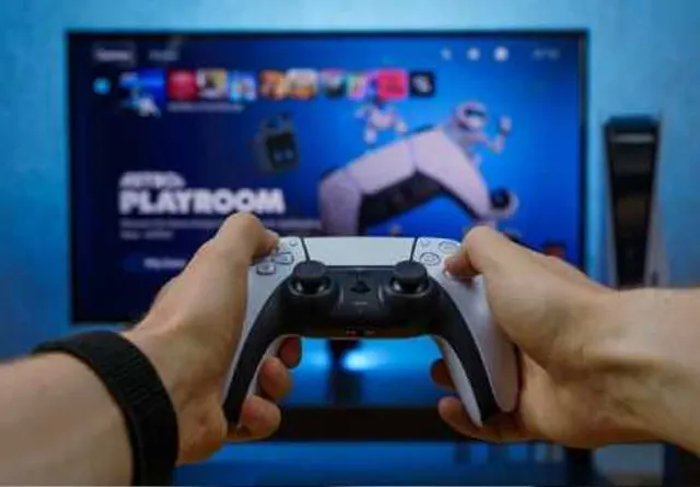 Player holding a game controller in front of a game menu on a screen