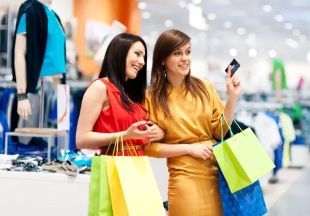 Happy shoppers with bags paying by card, representing a WooCommerce online store